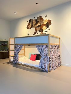 a bunk bed with curtains on it in a room that has white walls and flooring