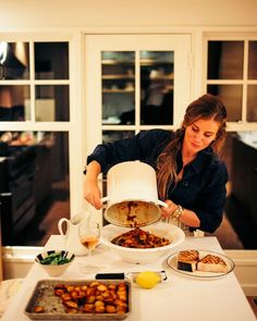 a woman pours water into a pot on top of a table filled with food