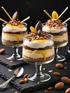 three desserts with almonds and chocolate on top are sitting in small glass dishes