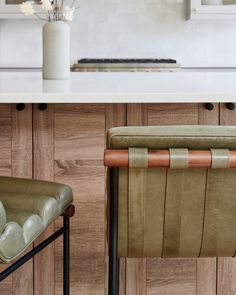 two green chairs sitting on top of a counter next to a vase with flowers in it