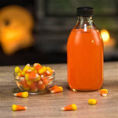 a glass bottle filled with liquid next to candy corn