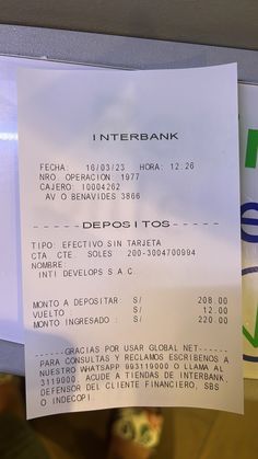 a receipt is hanging on the wall in front of a computer monitor that displays information about an interbank