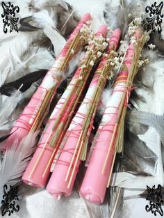 four pink candles with white and gold trims on feathers, one has flowers in the middle