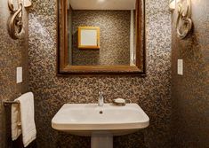 a bathroom sink sitting under a mirror next to a wall mounted light