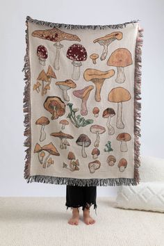 a woman standing in front of a blanket with mushrooms on it and fringes around the edges