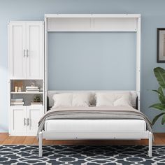 a white bed sitting on top of a wooden floor next to a wall mounted cabinet