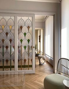 a living room filled with furniture next to a glass wall covered in art nouveau designs