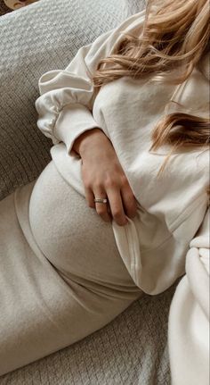 a pregnant woman laying on top of a couch