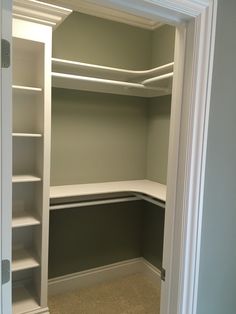 an empty walk in closet with shelves and carpet