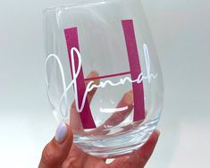 a hand holding a wine glass with the word hannah painted on it's side