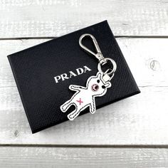 a keychain with the word prada on it and a small white dog