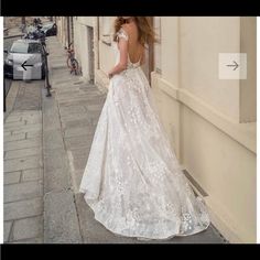 a woman in a white wedding dress standing on the side of a building with her back to the camera