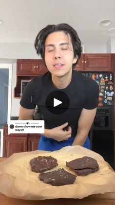 a man standing in front of a wooden table with chocolate cookies on top of it