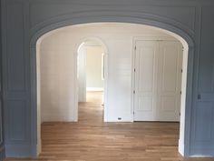 an archway leading to another room with wood floors and white painted walls, along with hardwood flooring