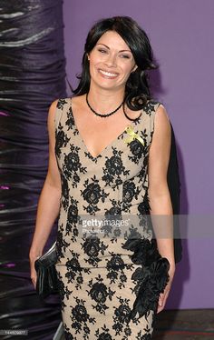 a woman in a black and white dress smiles as she stands against a purple wall