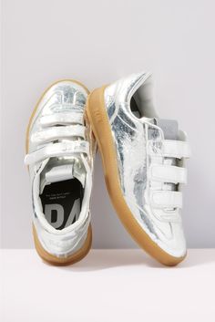 Add some shine to your look with these silver metallic sneakers by P448, featuring a low-top silhouette with a velcro closure, amber tread, and comfy memory foam insole. Each pair of P448 sneakers is crafted to maximize comfort, while the unexpected color combinations, textures, and patterns add a unique flair. All P448 sneakers are designed and made in Italy. | P448 Women's Monza Velcro Sneakers, Size 41, Silver Silver Sneakers With Removable Insole, Silver Sneakers With Removable Insole And Round Toe, Modern Metallic Silver Sneakers With Round Toe, Modern Metallic Silver Round Toe Sneakers, P448 Sneakers, Unexpected Color Combinations, Fall Closet, Velcro Sneakers, Metallic Sneakers