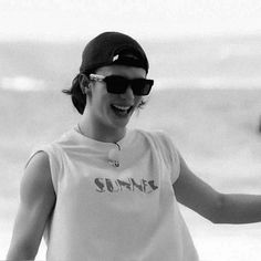 black and white photograph of a woman in sunglasses holding a frisbee on the beach