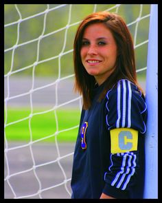 a woman standing in front of a soccer net with her arm around the goalie's shoulder