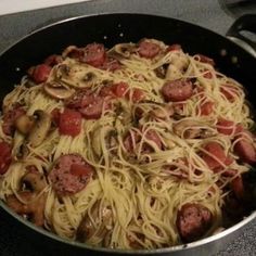 a pan filled with pasta and sausage on top of a stove