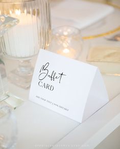 a close up of a card on a table with wine glasses and candles in the background