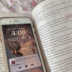 an open book with music playing on the screen next to an iphone and headphones