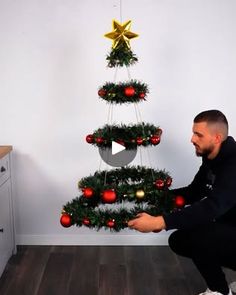 a man kneeling down in front of a christmas tree