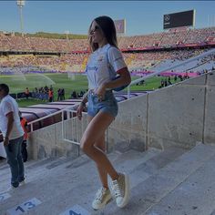 a woman is walking up some stairs at a stadium