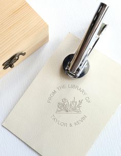 a wooden box with a pen on top of it next to a paper and stamp