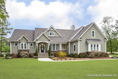 a large gray house sitting on top of a lush green field