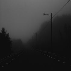 a foggy road with power lines and telephone poles in the foreground on a dark day