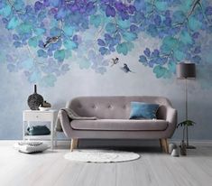 a living room with blue and purple flowers painted on the wall, white flooring and a gray couch