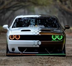 a white sports car with green eyes on the front is parked in a dirt road