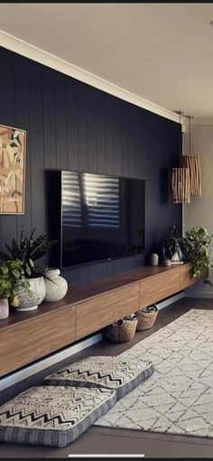 a living room filled with furniture and plants on top of a wooden shelf in front of a flat screen tv