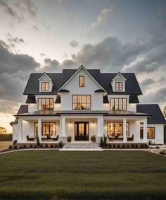 a large white house with lots of windows and grass in the front yard at dusk