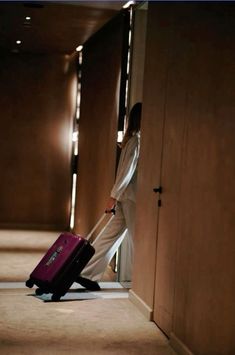 a woman is pulling a suitcase down the hall with her feet in the door way