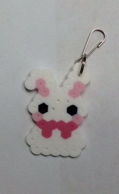 a white and pink keychain with a bunny on it's face in the shape of a dog