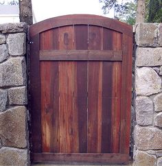 an open wooden gate on top of a stone wall