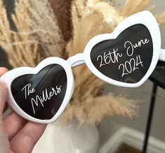 a person holding up two heart shaped sunglasses with the date on them and year written in white