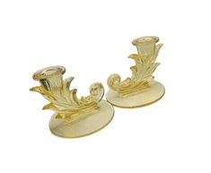 a pair of gold candlesticks with leaves on them sitting on top of each other