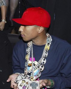 a young man wearing a red hat and necklace holding a skull shaped object in his hands