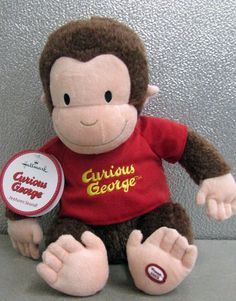 a stuffed monkey wearing a curious george t - shirt sitting on a table with a tag