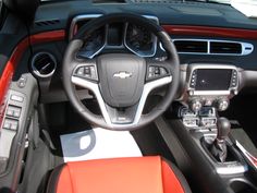 the interior of a sports car with orange and black leather seats, steering wheel and dashboard