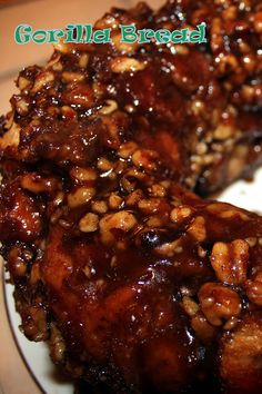 two pieces of meat covered in sauce and nuts on a white plate with green lettering