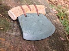 a piece of rock with a leather cord attached to it sitting on top of a tree trunk