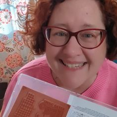 a woman wearing glasses holding up a stamp