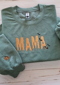 Welcome to my store! This sweatshirt features an embroidered Spooky ooze font with the word "mama" in the middle of sweater, and a pumpkin on the right outer lower wrist. The thread color is orange but if you prefer a different color, kindly specify it in the personalization box. "Stay cozy and stylish in this personalized embroidered sweatshirt! Made with high-quality material, this sweatshirt is designed to keep you warm and comfortable. The word 'mama' is beautifully embroidered on the front, Casual Halloween Top With Embroidered Logo, Custom Embroidery Long Sleeve T-shirt For Fall, Casual Halloween Sweatshirt With Custom Embroidery, Green Top With Letter Embroidery For Fall, Green Letter Embroidery Sweatshirt For Fall, Green Sweatshirt With Letter Embroidery For Fall, Halloween Embroidered Cotton Sweatshirt, Embroidered Cotton Sweatshirt For Halloween, Halloween Long Sleeve Sweatshirt With Custom Embroidery