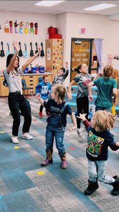 a group of children in a room with their arms up and one child on the floor