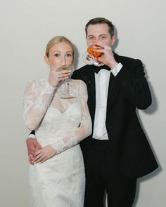 a man and woman standing next to each other holding drinks in front of their mouths