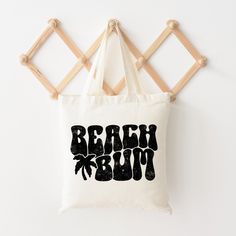 Looking for a cute tote bag to carry all your essentials this summer? This cute Beach Bum Palm Tree bag will be perfect to add to your collection. Perfect for a day at the beach or every day life! Casual Beach Shoulder Bag With Letter Print, Vacation Rectangular Shoulder Bag With Letter Print, Cute White Shoulder Bag For The Beach, Rectangular Shoulder Bag With Letter Print For Vacation, Rectangular Letter Print Shoulder Bag For Vacation, Trendy Cotton Bags For Vacation, Rectangular Letter Print Beach Bag, Rectangular Letter Print Bags For Vacation, Summer Vacation Bag With Letter Print