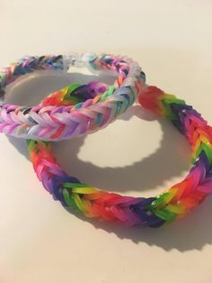 two different colored bracelets sitting on top of a white table next to each other